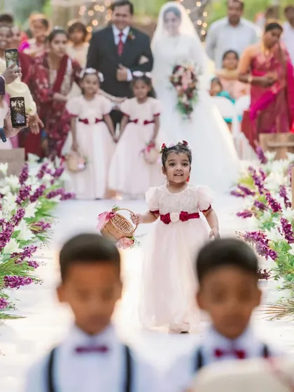 The little details make the biggest impression. A flower girl walks down the beautifully decorated floral aisle, a heartwarming moment that kicks off the wedding ceremony.