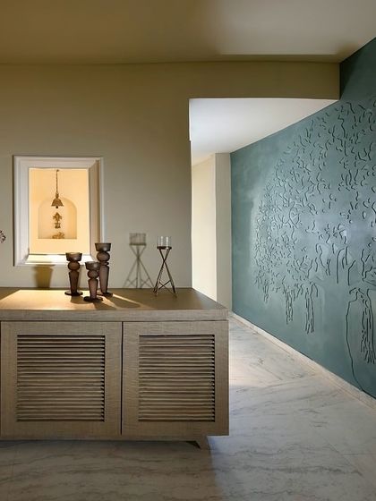The entrance to this home features a 'Tree of Life' motif, hand-carved into a teal-coloured feature wall. It’s a detail that immediately sets a tone of artistry and connection to nature, welcoming you into a harmonious space.