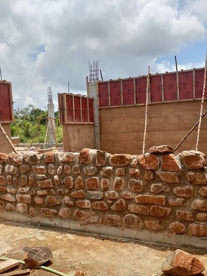 The construction of a community center, showing a combination of rubble masonry from local stone and formwork for mud concrete walls. This highlights our use of diverse, site-appropriate materials.