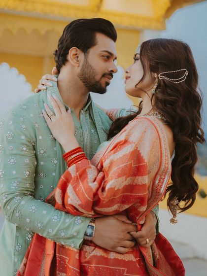 A warm, romantic embrace between the couple, set against the beautiful architecture of Udaipur.