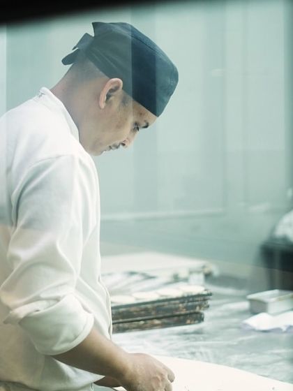 A chef at work, seen through the kitchen window. It's a demanding job with long hours, but the reward of a job well done is immense.