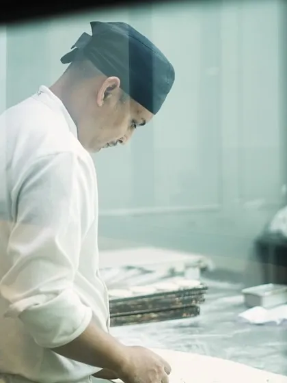 A chef at work, seen through the kitchen window. It's a demanding job with long hours, but the reward of a job well done is immense.