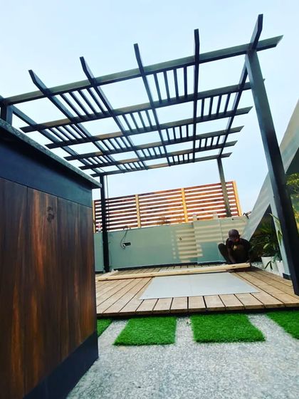 A view from behind the bar counter, showing the spacious layout of the pergola and deck area, with a wooden privacy wall in the background.