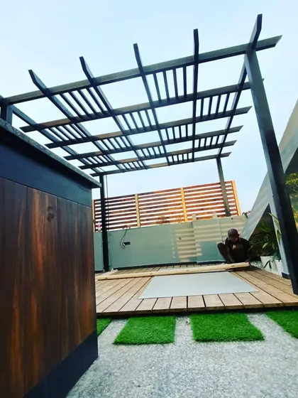 A view from behind the bar counter, showing the spacious layout of the pergola and deck area, with a wooden privacy wall in the background.