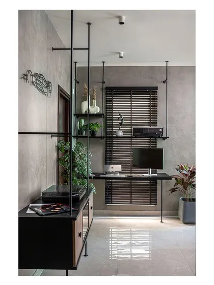 The study room features grey textured walls and a custom suspended shelving and desk system. The black metal and wood elements create an industrial yet rustic ambiance, perfect for a comfortable and productive workspace.