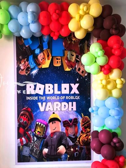 I brought the world of Roblox to life for Vardh's birthday party at home. This decoration features a large, framed poster of the game's characters, surrounded by a vibrant, rainbow-colored balloon arch.