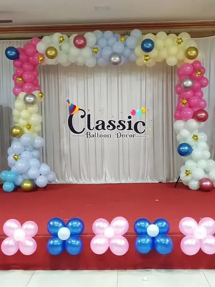 A large stage decoration for a baby shower, featuring multiple balloon arches and swing-like structures for a playful and grand look.