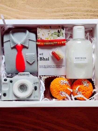 A Rakhi hamper for a brother who loves photography. It includes a camera soap, a shirt-and-tie soap, body wash, and scented ladoo candles.
