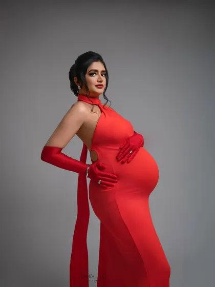 A portrait of pure confidence. The backless detail and form-fitting silhouette of this red gown are designed to celebrate your changing body with style and grace. This is maternity fashion at its boldest.
