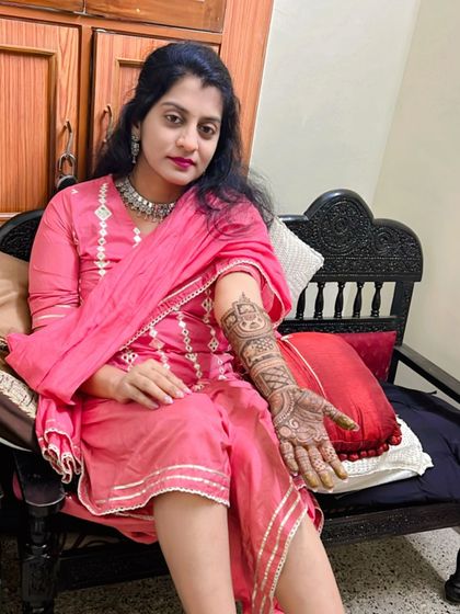A beautiful bride in a pink outfit, her full bridal mehendi looking stunning as she poses for a photo.