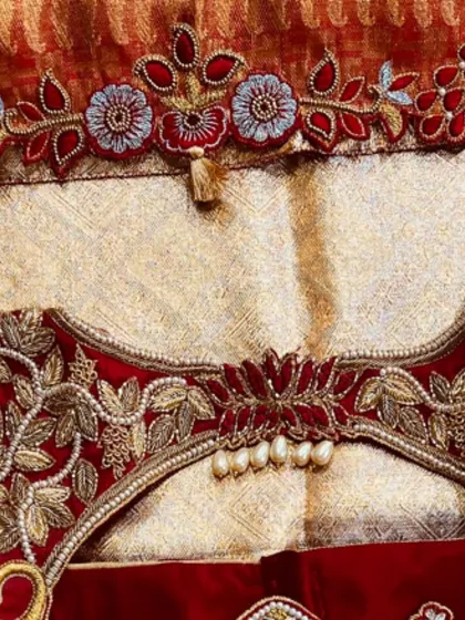 The back of the blouse, showing how the floral embroidery and pearl details come together. The central pearl tassel is a key focal point.