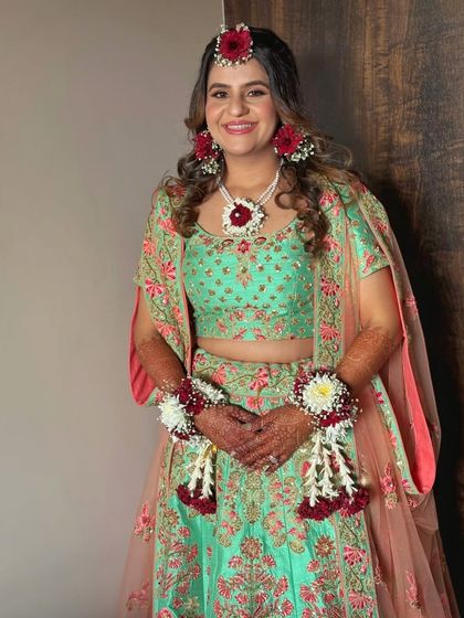 A full-length portrait of the bride in her mint green and pink Haldi outfit. The makeup is soft and fresh, perfect for a daytime celebration.