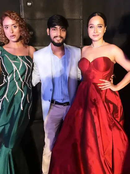 Posing with my models after a successful show. The red ball gown and the green mermaid gown with its unique branch-like embroidery showcase the range of my couture designs.