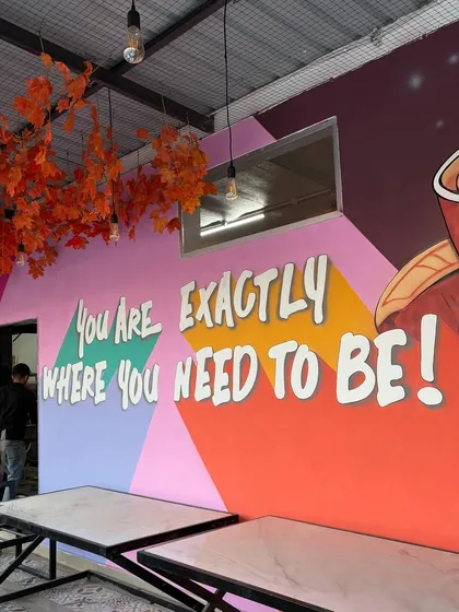 The motivational quote wall seen from a different angle, with tables in the foreground, showing how the art integrates into the functional space.