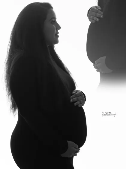 An artistic double-exposure style portrait. This black and white image creatively combines a profile shot with a close-up of the baby bump, telling a story of inner and outer beauty.