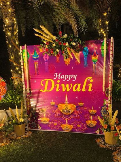 A "Happy Diwali" photo booth set up in the garden, decorated with floral arrangements and traditional props.