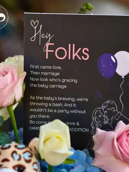 A custom invitation card with a sweet poem, nestled in a bouquet of pink and white roses.