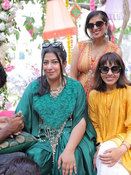The bride poses with her friends while getting her mehendi done, capturing the happy, social atmosphere.