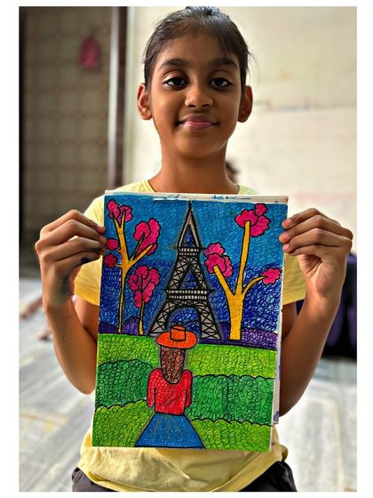 A 4th-grade student shows her whimsical drawing of the Eiffel Tower, combining line work with doodling techniques. We explore different ways to fill spaces and add texture to our art.