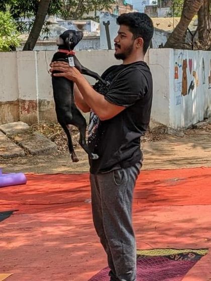 A participant holds up a small black puppy in a "Lion King" pose during an outdoor yoga session at the humane animal society.