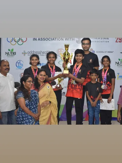 Our rifle event champions holding their team trophy at the Best Shot Open Competition, joined by their proud parents and coaches.