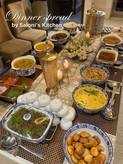 A beautifully styled dinner party spread in a home setting, featuring a mix of Indian dishes in classic blue and white pottery.