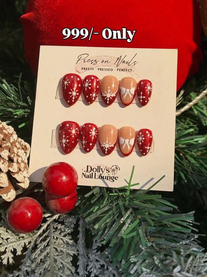A sweet Christmas press-on set with snowy red nails, white bows, and delicate snowflake designs.