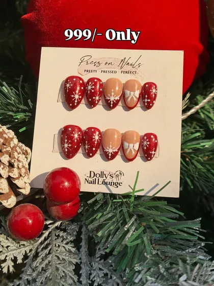 A sweet Christmas press-on set with snowy red nails, white bows, and delicate snowflake designs.