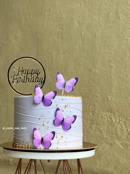 A close-up of a purple butterfly cake with delicate line work and gold sprinkles.