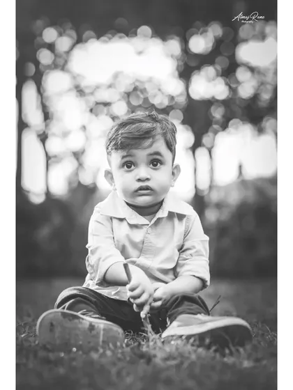 A soulful black and white portrait of Ivaan sitting in the grass. The soft focus and his direct gaze make this a simple but deeply engaging photograph.