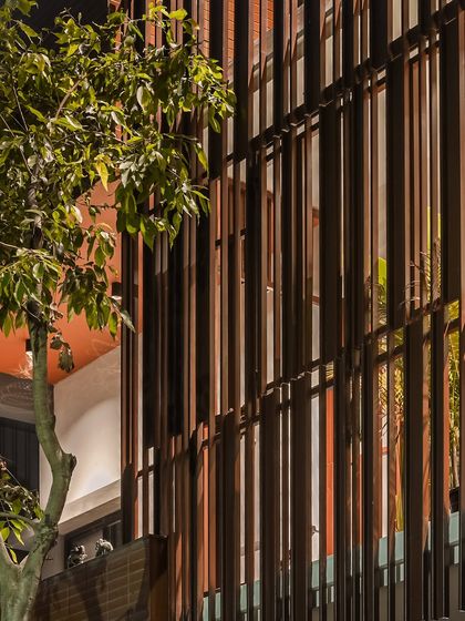 A nighttime view of the 'Ittige' facade, where the interior light filters through the vertical fins. The house transforms into a lantern, revealing the life within and creating a warm, inviting glow.
