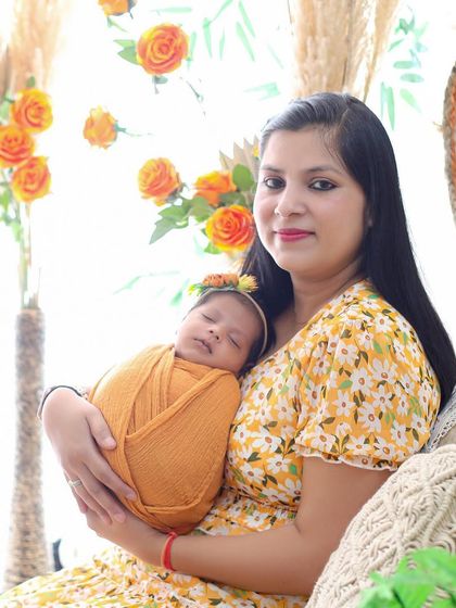 A beautiful mother and daughter portrait. The new mom holds her sleeping baby, both surrounded by the warm, bright colors of our bohemian studio setup.