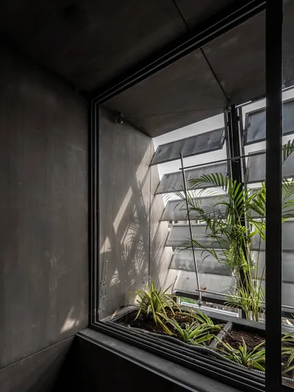 An interior view of a workspace in Green Park, New Delhi, showing the effect of the adjustable louver system. This 'plug-in' facade allows users to control the amount of natural light, with integrated planters that bring greenery directly into the window frame. It's a functional system that connects the office interior to the outside environment.