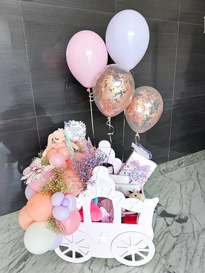 The pink chariot hamper, complete with confetti balloons, ready to celebrate a baby girl's arrival. This grand gift is designed to make a lasting impression.