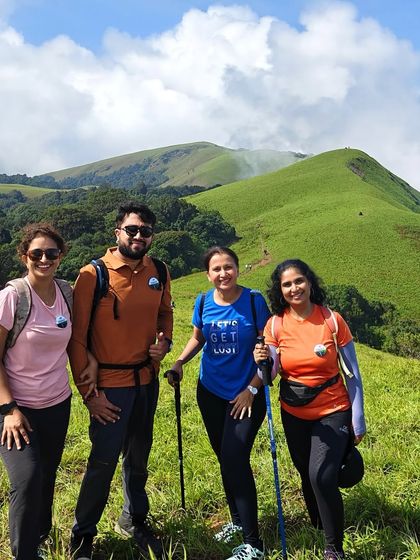 Our trekkers, equipped with walking sticks, pose against the stunning backdrop of the green hills of Bandaje.