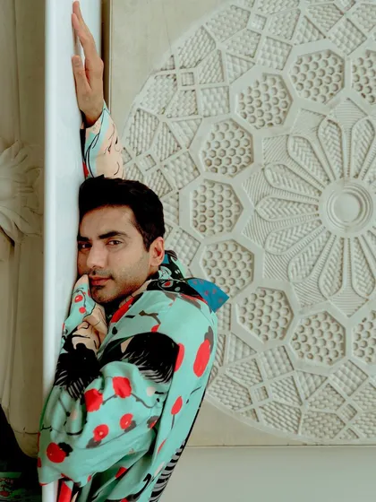 A close-up portrait of Ishwak Singh for HT City. The composition uses the patterned wall and the lines of the garment to frame the actor's face.