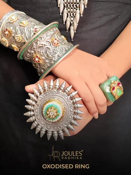 Boldness crafted in silver. This oxidized kada and oversized ring are for the woman who wears her heritage with modern confidence. The intricate carvings and gemstone accents make these pieces a testament to powerful, statement-making design.