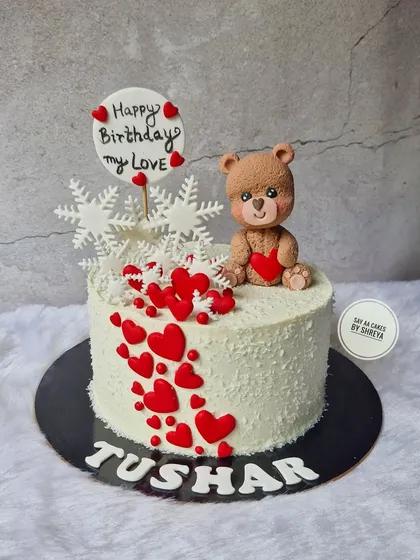 A cake that's full of love. This design features a cascade of red hearts, delicate snowflakes, and an adorable teddy bear holding a heart, making it a perfect birthday cake for a loved one.