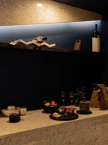 A close-up of the bar counter styling. The warm, indirect lighting from above and below the floating shelf creates an intimate mood, perfect for highlighting barware and creating an inviting atmosphere for entertaining.