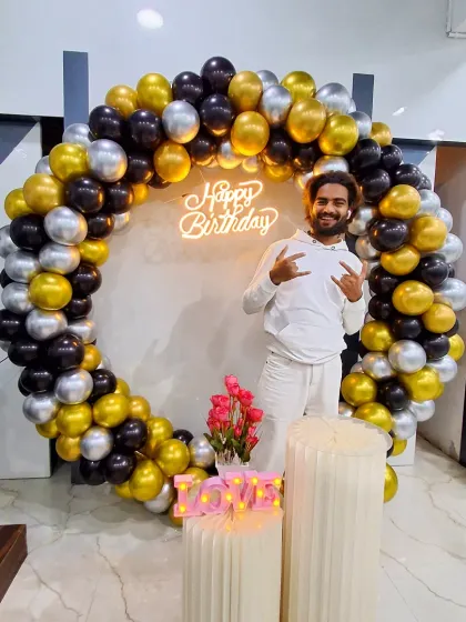 The birthday person enjoying the black, gold, and silver photo booth I created.