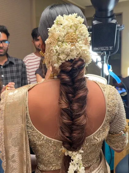 A back view of the South Indian bridal braid, captured on set. This angle shows the full length of the braid and the dense floral arrangement at the base, a hallmark of traditional South Indian hairstyling.