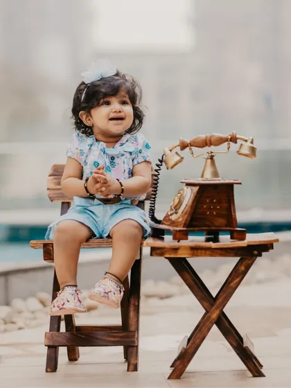 An adorable little girl sitting with a vintage telephone prop during her milestone photoshoot.
