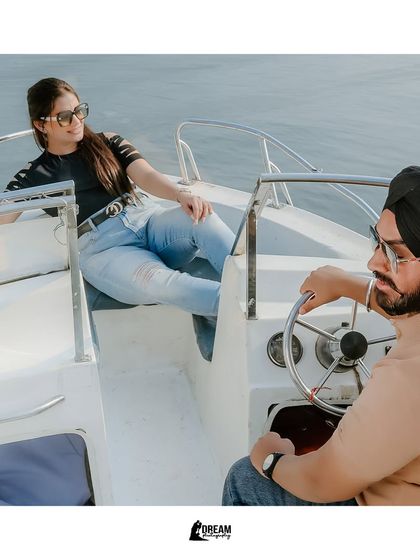 A cool, stylized shot of the couple on a boat, exuding a relaxed and confident vibe as they navigate the waters together.