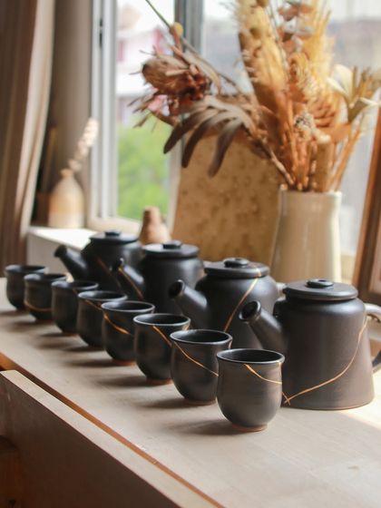 A set of four teapots and matching cups, each with a delicate gold line. These were part of my experiments to solve airflow and pressure issues to achieve a perfect pour.