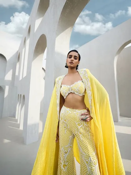 A breathtaking sharara set in yellow, fully embroidered like a tapestry woven from light. Paired with a flowing cape, it's a dance of radiance and grace.