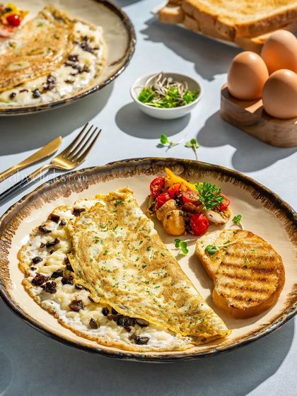 A fluffy, folded omelette with a mushroom filling, served with grilled toast and sauteed vegetables.