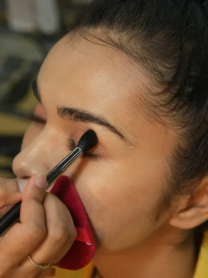 An artist carefully applies eyeshadow backstage. Our students learn to work with precision and speed to prepare models for the runway.