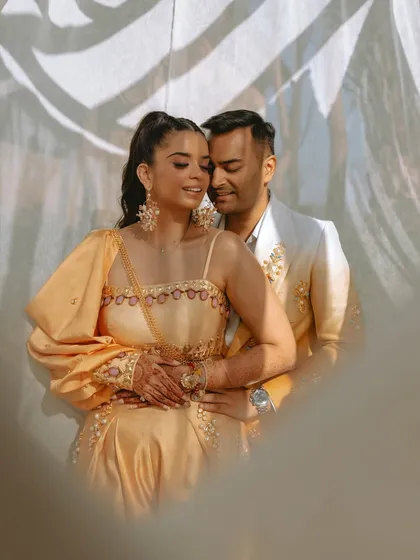A loving embrace, with the groom holding the bride from behind, both looking serene and happy.