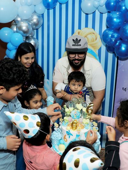 Another angle of the happy cake-cutting moment, with kids in party hats eagerly watching.