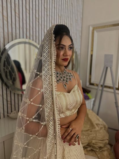 A behind-the-scenes shot of the model with a sheer, embellished dupatta over her head, adding a touch of bridal elegance to the modern lehenga.